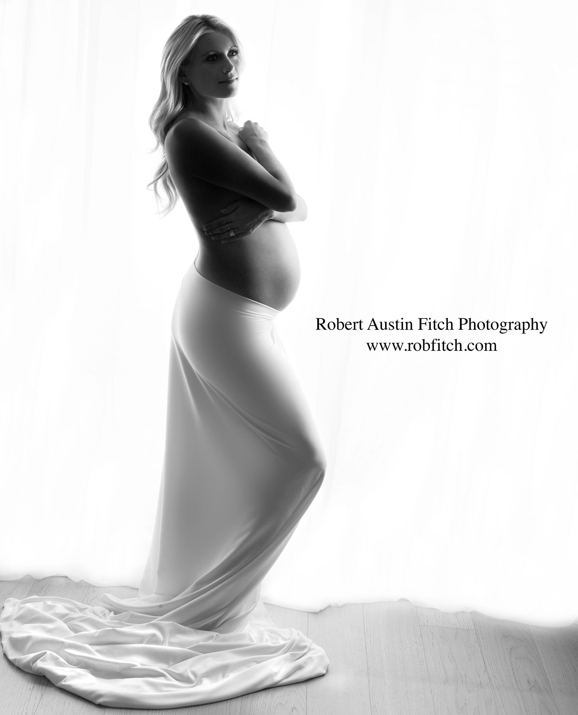 B&W silhouette maternity photo of pregnant woman with white fabric draped around her waist