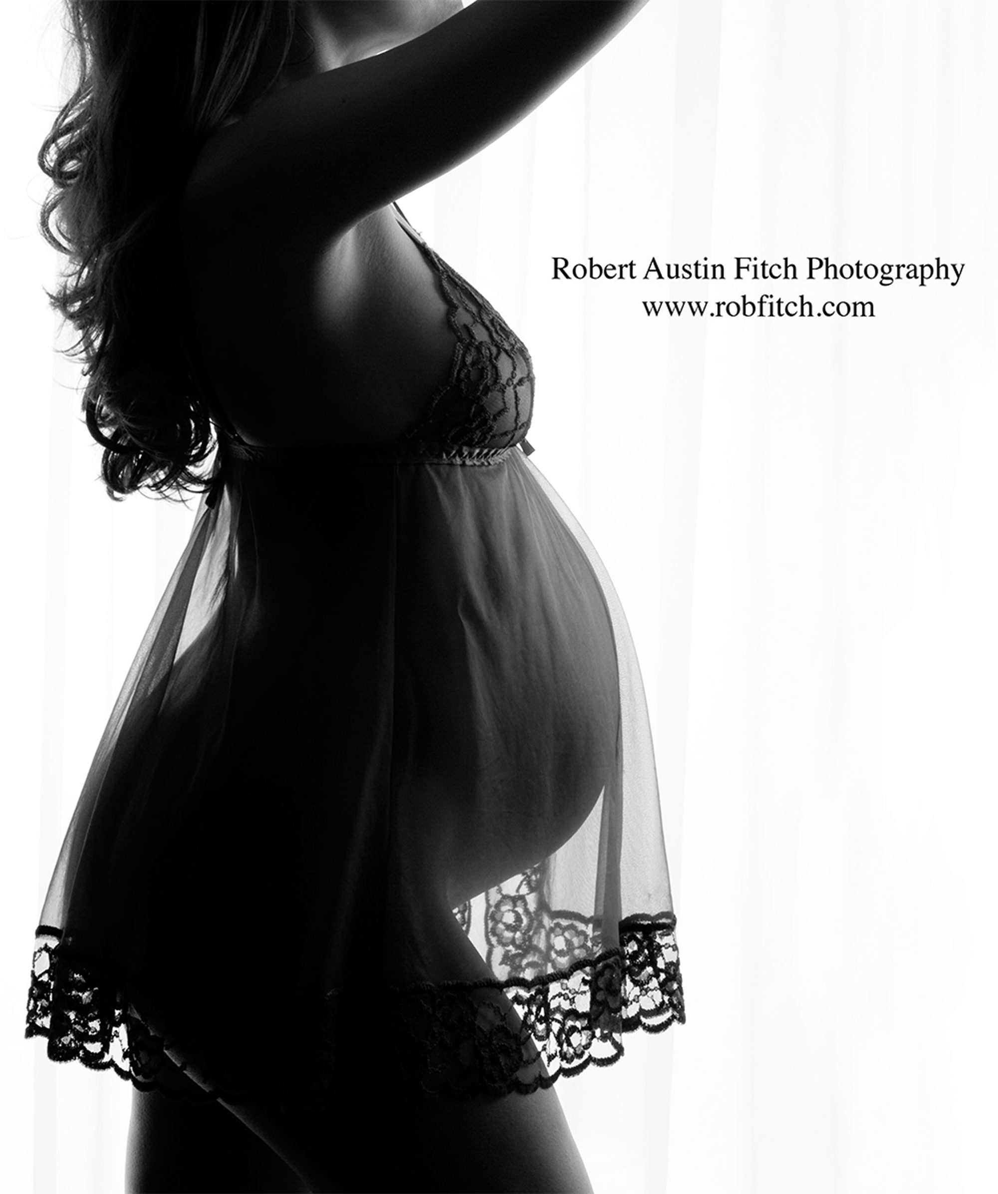 Black & white silhouette maternity photo of pregnant woman in black sheer negligee