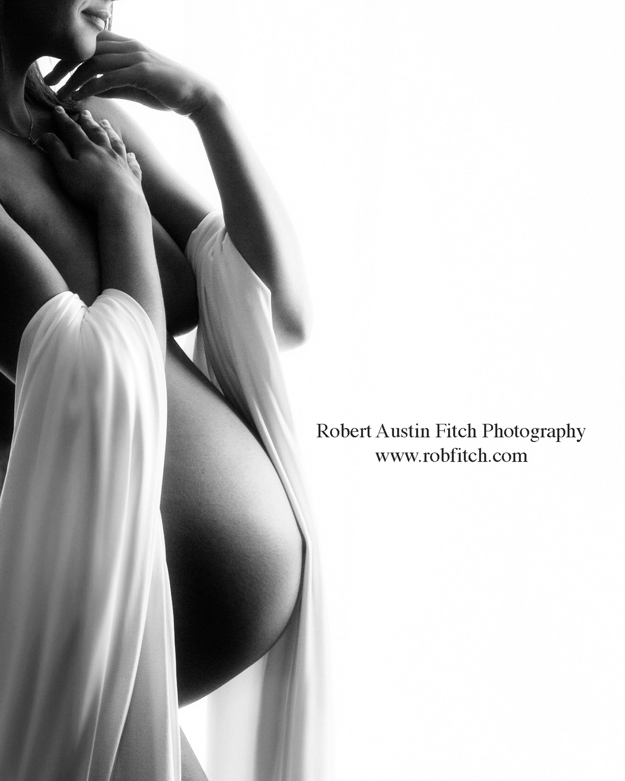 Artistic B&W silhouette maternity photograph of pregnant woman with white fabric draping