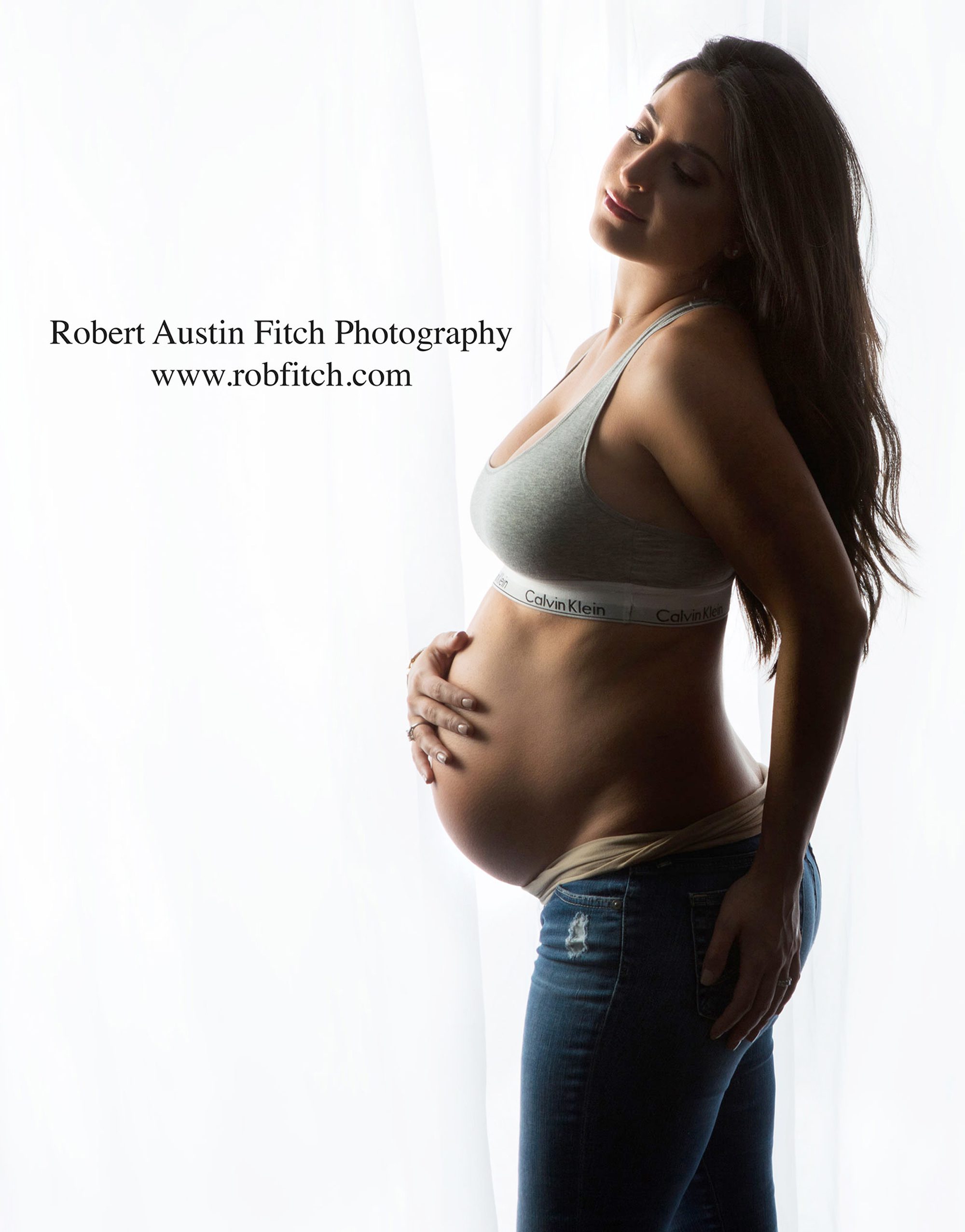 Silhouette photo of pregnant woman in jeans & a Calvin Klein sports bra