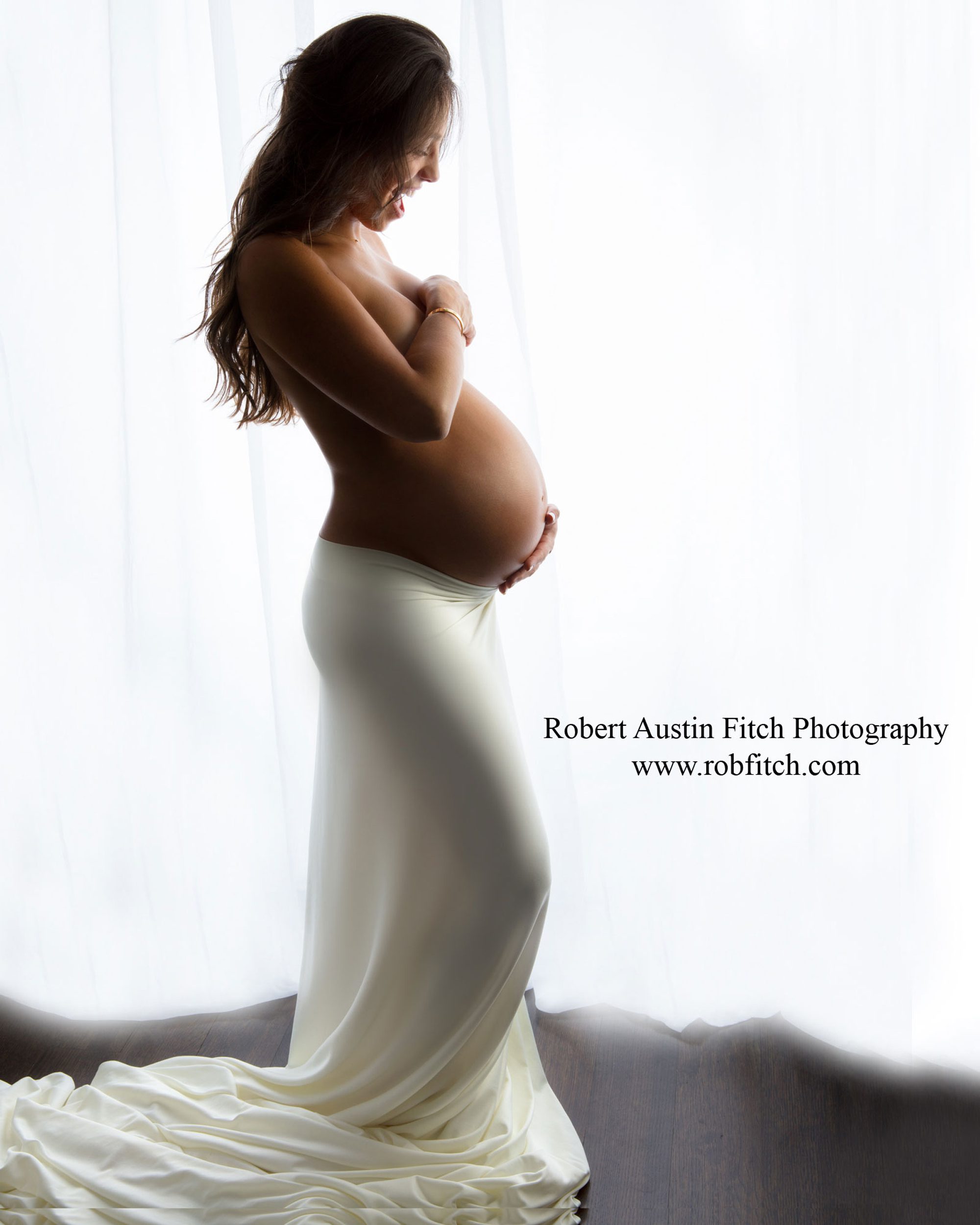 Artistic silhouette maternity photo of pregnant woman with white fabric draping